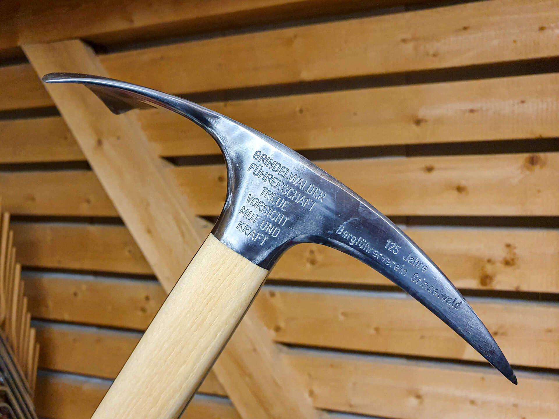 Ice pick with engraving in front of a wooden wall, no other equipment visible.