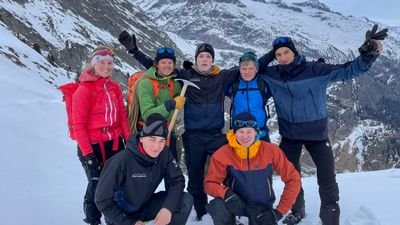 Gruppe von Personen mit Winterkleidung und Rucksäcken in schneebedeckten Bergen.