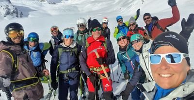 Gruppe von Personen mit Skiausrüstung und Helmen posiert im verschneiten Berggebiet.