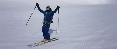 Person auf Skiern mit Stöcken und Helm in schneebedeckter Berglandschaft.
