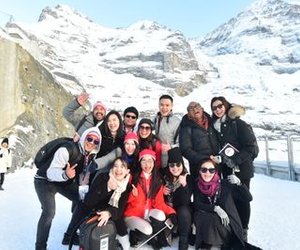 Group of people in winter clothing posing in front of snow-covered mountains.