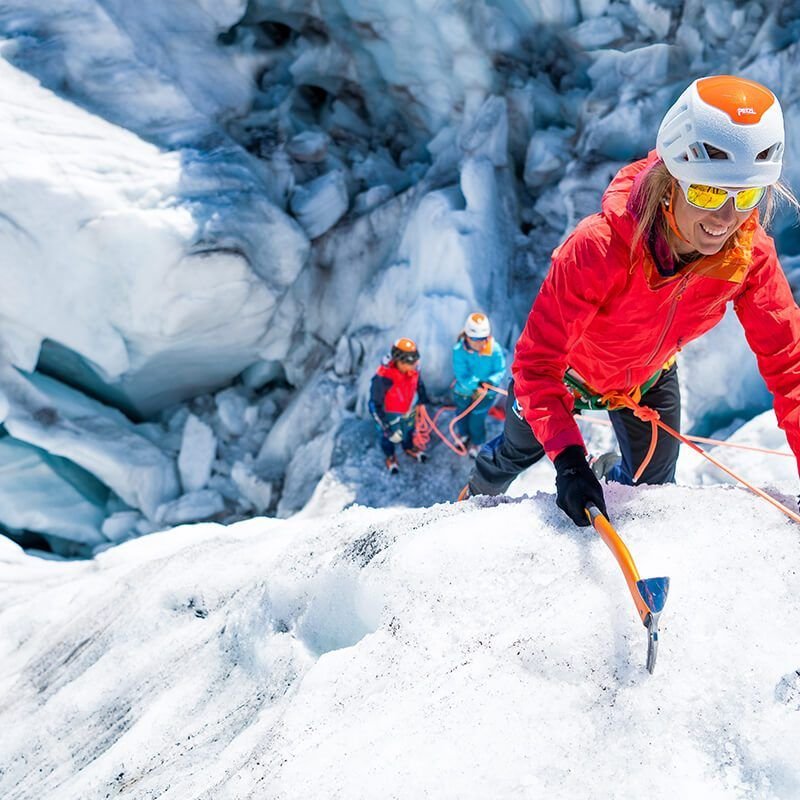 Mädchen erreicht die Spitze beim Eisklettern und lächelt.