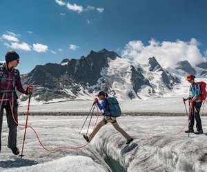 Gletscherwanderer einer Seilschaft macht einen grossen Schritt über eine Gletscherspalte