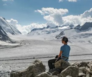 Person sitzt auf Stein bei der Konkordiahütte mit Blick über den Konkordiaplatz