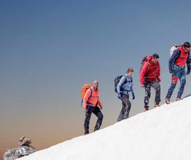 Mountaineers are hiking up a snowfield.