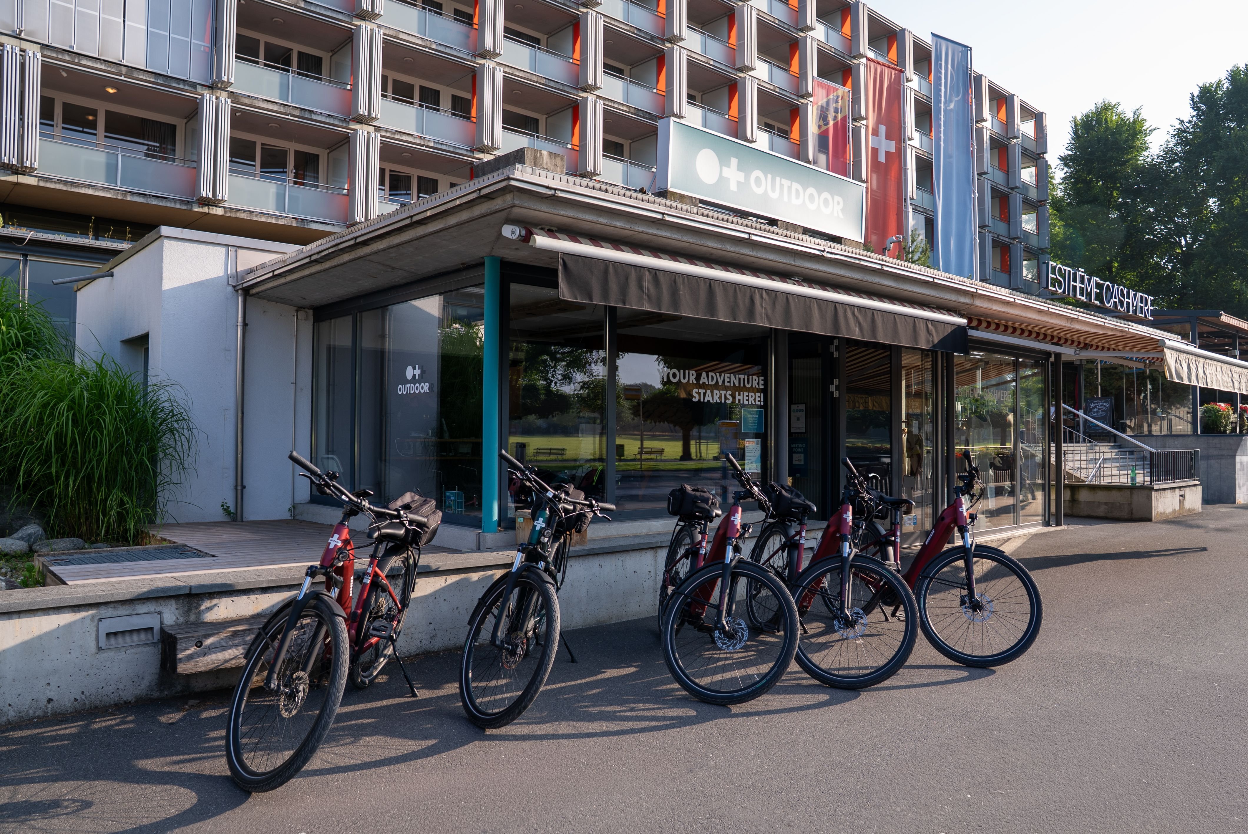 Bicycles parked outside an adventure company building with signage and a multi-story structure behind.
