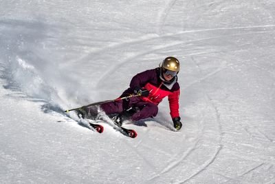 Person auf Skiern mit Helm fährt eine verschneite Piste hinunter.