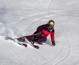 Person on skis with a helmet is skiing down a snowy slope.