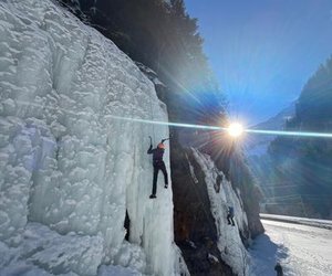 Person am Eisklettern mit Sonne im Hintergrund