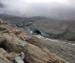 Rocky mountain landscape with visible glacier caves and overcast sky.