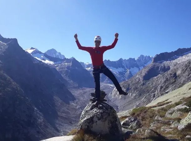 Mountaineer balancing on a rock with hands in the air