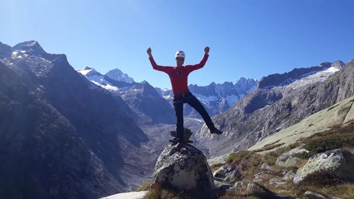 Bergsteiger balanciert auf Felsblock mit Händen in der Luft