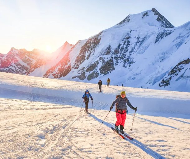 Ski tourers ascending with sunrise in the background
