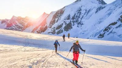 Ski tourers ascending with sunrise in the background