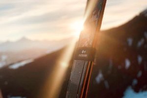 Skiing in front of a mountain landscape at sunset, snow visible on the mountain peaks.