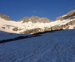 Snow-covered mountain landscape with rocky peaks under a clear blue sky.