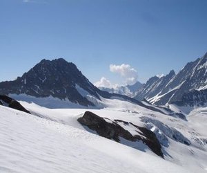 Snow-covered mountains under a clear blue sky, with rugged peaks and a vast glacier.