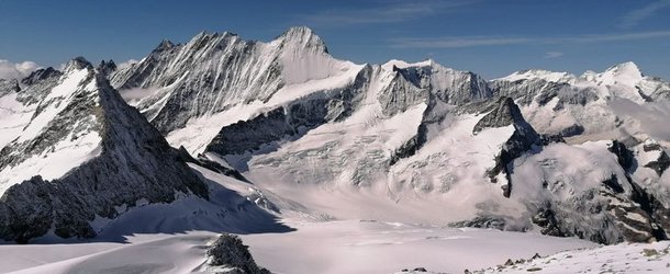 Snow-covered mountain peaks under a clear blue sky, with glaciers and rocky ridges visible.