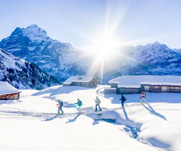 Skitourengänger im Aufstieg bei Alphütten mit dem Wetterhorn im Hintergrund