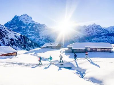 Ski tourers ascending near alpine huts with the Wetterhorn in the background.