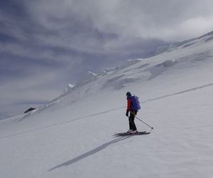 Ski tourers descending with a glacier calving in the background.