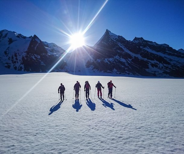 Ski tourers on the Konkordiaplatz with sunrise in the background.