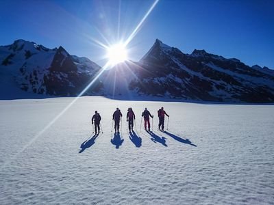 Ski tourers on the Konkordiaplatz with sunrise in the background.