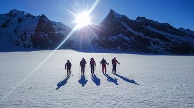 Ski tourers on the Konkordiaplatz with sunrise in the background.