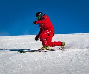 Person in red ski clothing and helmet skiing down a snow-covered slope.