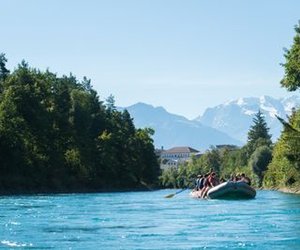 Inflatable boat drifting on the Aare between Thun and Bern, surrounded by trees, mountains in the background