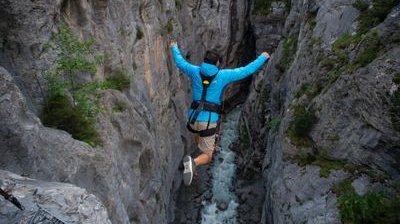 Person in blue jacket securely jumps into the glacier gorge in Grindelwald at the Canyon Swing
