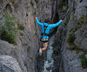 Person in blauer Jacke springt gesichert in die Gletscherschlucht in Grindelwald beim Canyon Swing