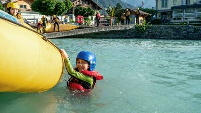 Child swims after the family rafting in the turquoise blue Lake Brienz.