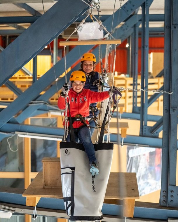 Zwei Personen überwinden lachend ein Hindernis im Indoor Seilpark Grindelwald