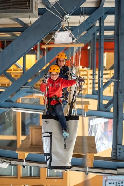 Zwei Personen überwinden lachend ein Hindernis im Indoor Seilpark Grindelwald
