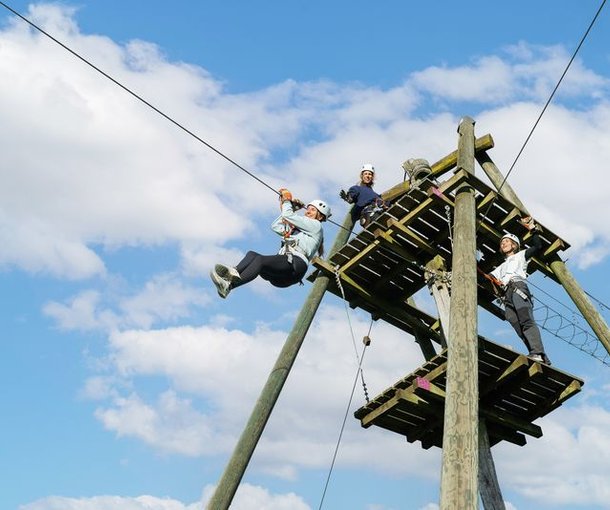 Several people are standing on a wooden platform in the Rigi rope park