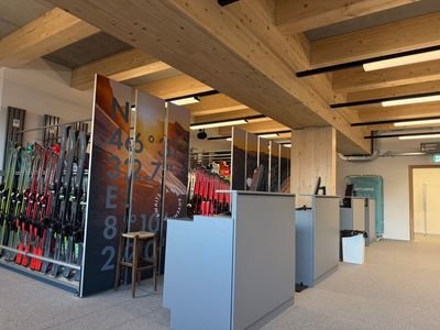 Ski rental with shelves full of ski equipment, wooden beam ceiling, and modern reception desk.